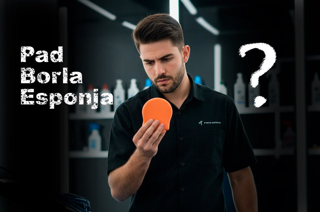 Un detallador profesional, vestido con camisa oscura, mira con gesto de confusión un pad de pulido naranja brillante que sostiene en su mano. Sobre su cabeza hay un signo de interrogación blanco y las palabras "Pad Borla Esponja" escritas en grande